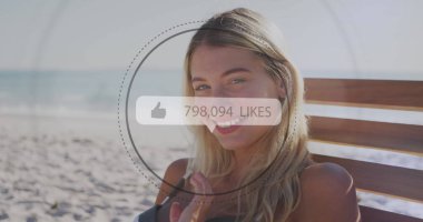 Like icons with increasing numbers against portrait of caucasian woman smiling at the beach. social media networking and vacation concept