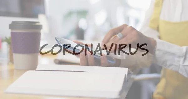 Image of flashing words with woman disinfecting smartphone in office wearing face masks. Healthcare and protection during coronavirus covid 19 pandemic, digitally generated image