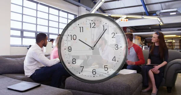 Image of clock ticking over diverse business people in office. Global finance, business, connections, computing and data processing concept digitally generated image.