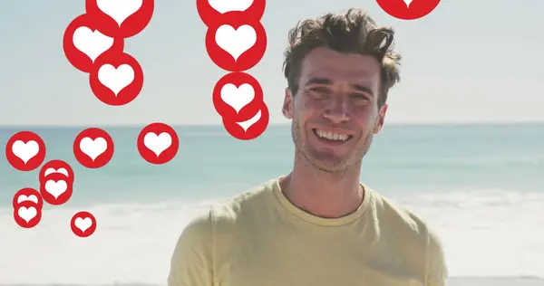Image of social media heart icons over portrait of smiling man on beach. digital interface, social media and global network concept digitally generated image.