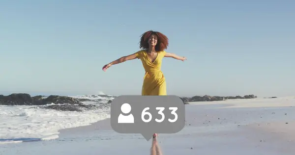 Image of speech bubble with people icon and numbers over woman spinning on beach. digital interface, social media and global network concept digitally generated image.