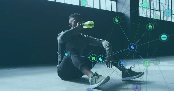 Image of network of connections with technological icons over man pouring water on head. Digital interface global sport and performance concept digitallygenerated image.