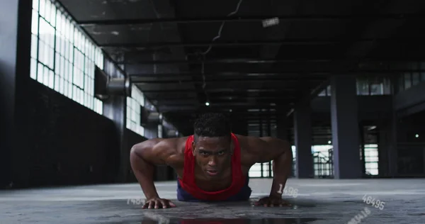 Image of falling numbers over man doing push ups in an abandoned building. Digital interface global sport and performance concept digitallygenerated image.