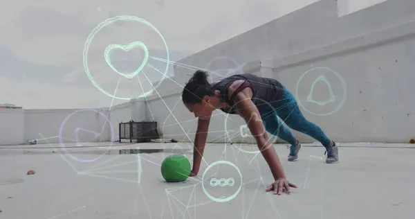 Image of technological icons over woman exercising with a ball. Digital interface global sport and performance concept digitallygenerated image.