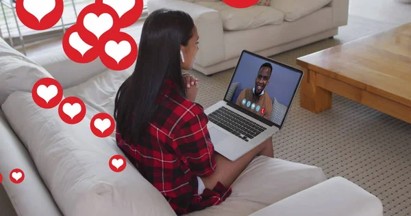 Image of social media heart icons over woman using laptop of image call in background. Digital interface global social media connection and communication concept digitally generated image.