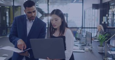 Asyalı kadın ve melez genç adam modern bir ofiste işbirliği yapıyorlar. Proje üzerinde yoğunlaşıyorlar, profesyonel bir ortamda takım çalışması sergileniyor.