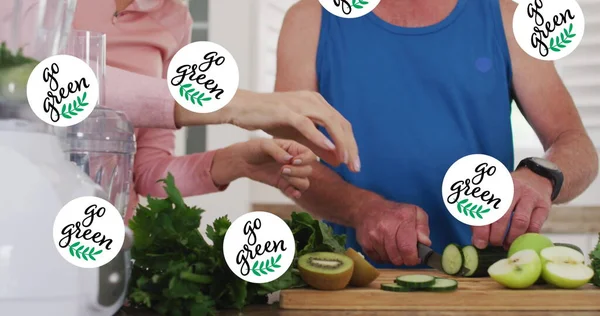 Image of go green text over senior caucasian couple cooking. senior home hangout and digital interface concept digitally generated image.