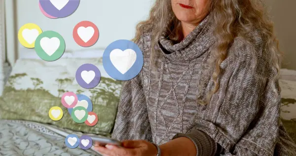 Image of digital heart icons over woman using smartphone. global social media, digital interface, technology and networking concept digitally generated image.