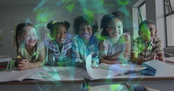Image of glowing network over smiling diverse schoolchildren at desk in classroom. Communication, friendship, school, education, childhood and learning, digitally generated image.
