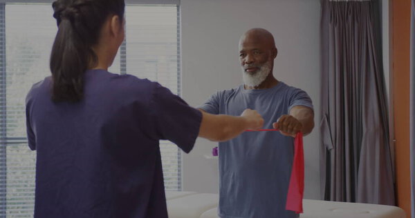 Senior African American man exercises with a therapist at a rehabilitation center. 