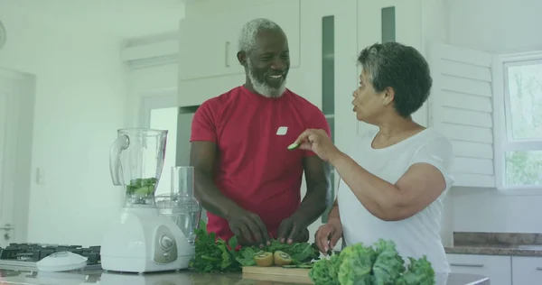 Image of bio super foods texts over senior african american couple cooking. senior home hangout and digital interface concept digitally generated image.