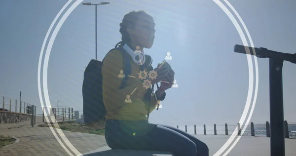 Image of technological icons over woman eating sandwich on promenade by the sea. Digital interface global sport and performance concept digitallygenerated image.