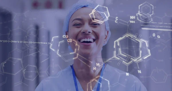 Image of medical data processing over smiling biracial female doctor in hospital. Global medicine, healthcare, digital interface, computing and data processing concept digitally generated image.
