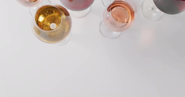 多种颜色的眼镜与红色 玫瑰和白色的葡萄酒在白色背景的复合 酒和酒精概念 — 图库视频影像