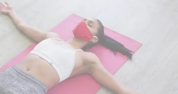 Coronavirus concept, woman wearing face mask lying on yoga mat. coronavirus covid-19 pandemic and fitness concept