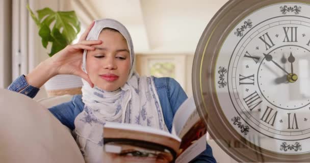 Animation Klocka Över Biracial Kvinna Hijab Läsa Bok Och Leende — Stockvideo