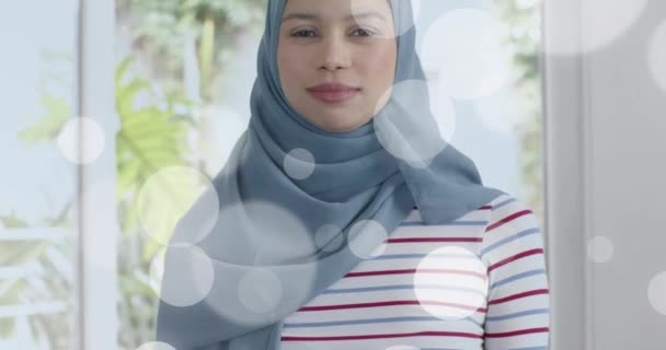 Animering Ljusfläckar Över Biracial Kvinna Hijab Tittar Kameran Livsstil Hushållsliv — Stockvideo