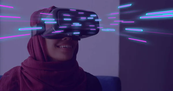 Image of glowing light trails of data transfer over biracial woman in vr headset. Global virtual reality, data processing, computing and digital interface concept digitally generated image.