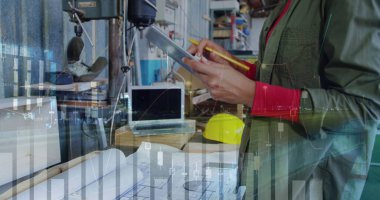 Tabletli kadın mühendis planları, dükkanda grafikler.