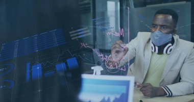 Yüz maskeli bir işadamının ofiste notlar alırken çekilmiş mali veri görüntüsü. covid 19 salgın konsepti dijital olarak oluşturulmuş görüntü sırasında küresel iş ve dijital arayüz.