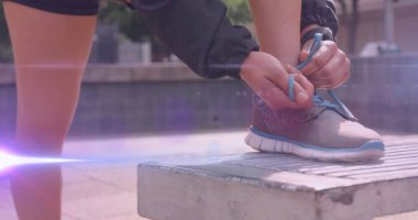 Koşu ayakkabısı bağlayan şortlu bir kadının ayakları üzerinde hareket eden ışık görüntüsü. Tatiller, sağlıklı, aktif yaşam tarzı ve pozitiflik kavramı dijital olarak oluşturuldu.