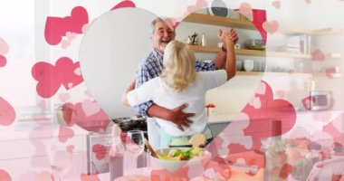 Mutfakta dans eden yaşlı beyaz çift yerine kalp animasyonu. Aşk, ilişki ve eğlence konsepti dijital olarak oluşturulmuş video.