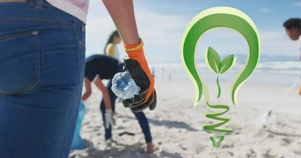 Image of go green light bulb logo over diverse group picking up rubbish from beach. eco conservation volunteer month digitally generated image.