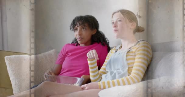 在家里观看爆米花电影的两个快乐的 多样化的少女身上动画的电影框架 娱乐和生活方式 数码录像 — 图库视频影像