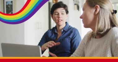 Onurlu gökkuşağı çizgilerinin animasyonu mutlu beyaz lezbiyen çiftin üzerinde dizüstü bilgisayar kullanarak ve konuşarak. Ev hayatı, iletişim, Igbtq, gay, lezbiyen, gurur ve yaşam tarzı, dijital olarak üretilen video.