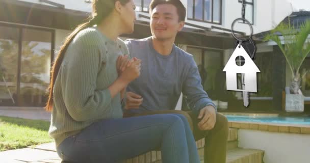 家の庭で幸せな多様なカップルに銀の家のキーとキーフォブのアニメーション 所有権 ライフスタイルのコンセプトデジタル生成ビデオ — ストック動画