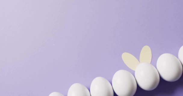 紫色の背景に白い卵の上に幸せなイースターテキストのアニメーション イースター お祝いのコンセプトデジタル生成ビデオ — ストック動画
