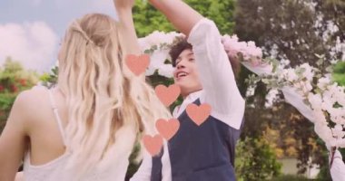 Evlilik gününde bahçede dans eden mutlu çiftin yerine pembe kalplerin animasyonu. Çift, evlilik, doğa, yaz, kutlama, birliktelik, aşk ve romantizm, dijital olarak üretilen video.