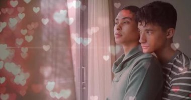 Pencereden dışarı bakan, kucaklaşan mutlu ve çeşitli eşcinsel çiftlerin üzerinde parlayan kalplerin animasyonu. Çift, aşk, ev hayatı, lgbtq ve yaşam tarzı, dijital olarak oluşturulmuş video.