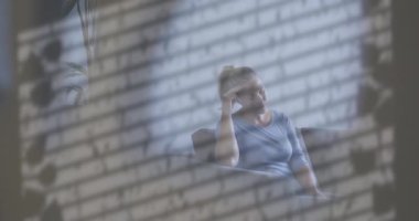 Pencerenin gölgesinin gölgesi ve evde oturan mutsuz beyaz kadın üzerindeki su damlacıkları. Üzüntü, stres, yalnızlık, depresyon ve akıl sağlığı, dijital olarak üretilen video.