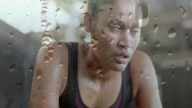 Yorgun Afrika kökenli Amerikalı bir kadının egzersizden sonra iyileşmesi üzerine su damlacıklarının canlandırılması. Fitness, egzersiz, yorgunluk ve sağlıklı yaşam tarzı, dijital olarak üretilen video.