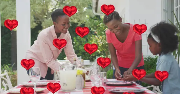 ハッピーなアフリカ系アメリカ人の家族が庭で夕食を準備するハート風船のイメージ コミュニケーション技術のコンセプトデジタル生成された画像 — ストック写真