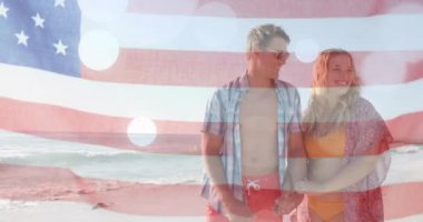Yazın plajda mutlu beyaz bir çiftin bayrağının canlandırılması. Amerikan vatanseverliği, çeşitlilik ve tatil konsepti dijital olarak oluşturulmuş video.