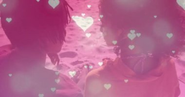 Sahilde kucaklaşan melez çiftin üzerine düşen kalplerin animasyonu. Yaşam tarzı ve doğa konsepti dijital olarak oluşturulmuş video.