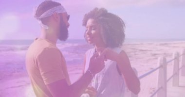 Sahilde kucaklaşan melez bir çiftin üzerindeki ışık lekelerinin canlandırması. Yaşam tarzı ve doğa konsepti dijital olarak oluşturulmuş video.