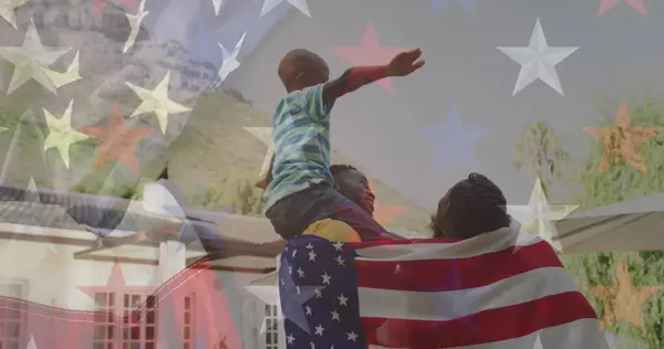 American flag design against african american couple wrapped in american flag carrying their son. american independence celebration and patriotism concept