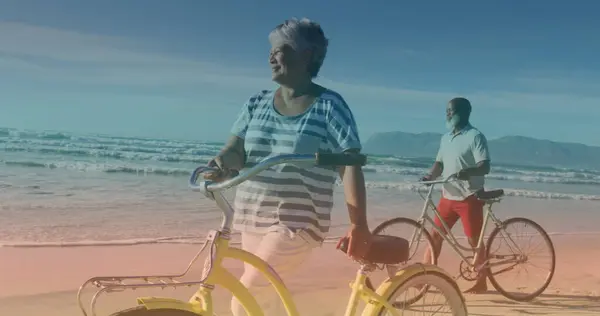 Пятна Света Против Африканской Старшей Пары Велосипедами Идущими Вместе Пляже — стоковое фото