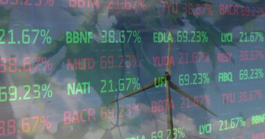 Dallardaki yapraklara karşı dönen yel değirmeni üzerinde işlenen borsa verilerinin görüntüsü. Küresel ekonomi ve yenilenebilir enerji teknolojisi kavramı