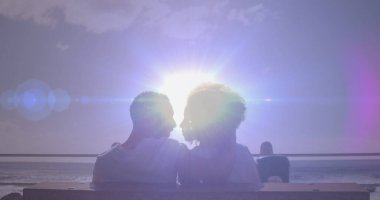 Sahilde öpüşen Afrikalı Amerikalı çifte karşı parlak bir ışık. Aşk ve ilişki kavramı