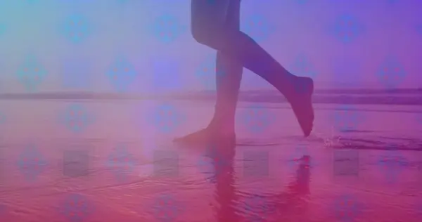 Pink square design pattern against low section of a woman walking on the beach. Love and relationship concept