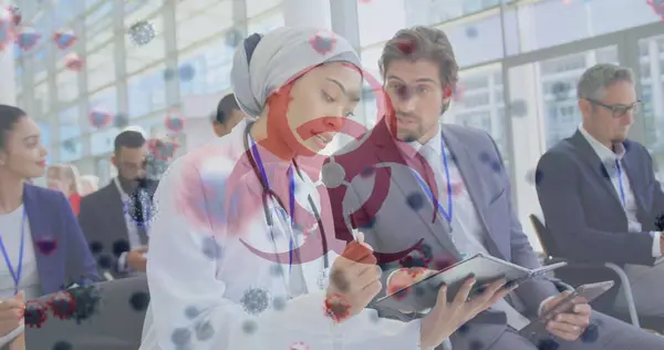 Image of a medical staff team during a conference with virus icon and coronavirus cells floating on the foreground. Covid 19 pandemic health care science medicine concept digital composite
