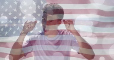 Güneşli plajda dans eden mutlu çift ırklı adamın üzerinde Amerikan bayrağı ve ışıklı noktaların animasyonu. Amerika, yaz, tatiller, sağlıklı yaşam tarzı, kutlama ve vatanseverlik, dijital olarak üretilen video.