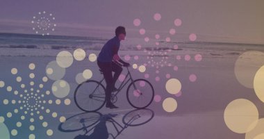 Sahilde bisiklet süren Afro-Amerikan bir adama karşı süzülen sarı ışık lekeleri. pedal gün farkındalığı kavramı