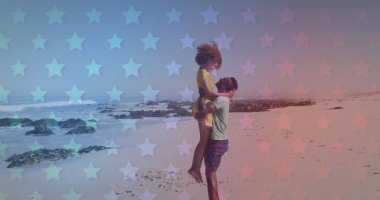 Genç Afrikalı Amerikalı çift yıldız desenli bir plajda kucaklaşıyor. Neşeli kaldırış bir neşe ve kaygısız bir bağ olduğunu gösterir..