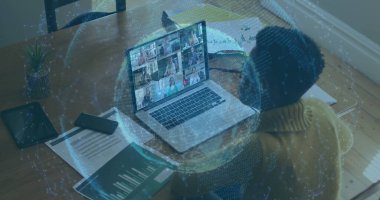 Evde dizüstü bilgisayarla çalışan genç bir Afro-Amerikalı kadın. Kağıtlar ve akıllı telefon uzaktan kumandalı cihazına eşlik ediyor, teknolojiyi konforla harmanlıyor..