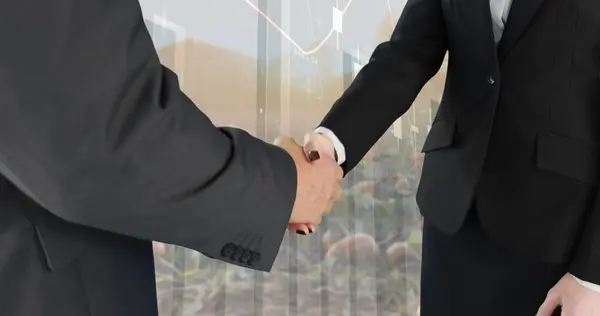 Close up of a handshake between a businessman and a businesswoman with a background of a field with crops. Digital image of graphs and statistics are running in the foreground